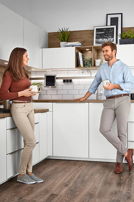 Couple discutant café à la main dans une cuisine blanche avec caissons XL et Maxi Couple discutant café à la main dans une cuisine blanche avec caissons XL et Maxi