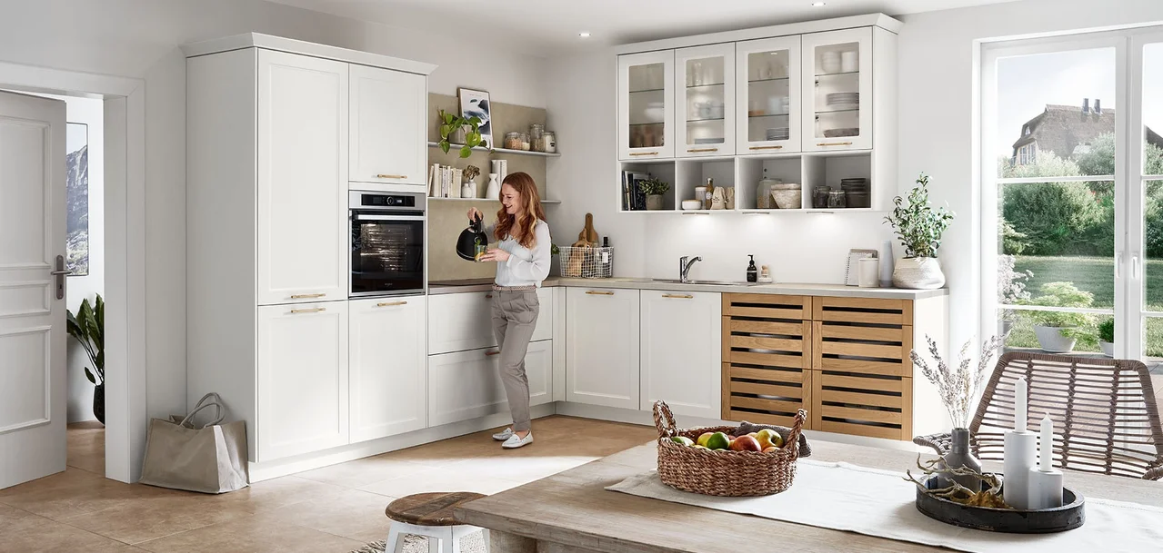 Cuisine en L blanche avec circulation dégagée, femme dans l'espace et vitrines vitrées Cuisine en L blanche avec circulation dégagée, femme dans l'espace et vitrines vitrées