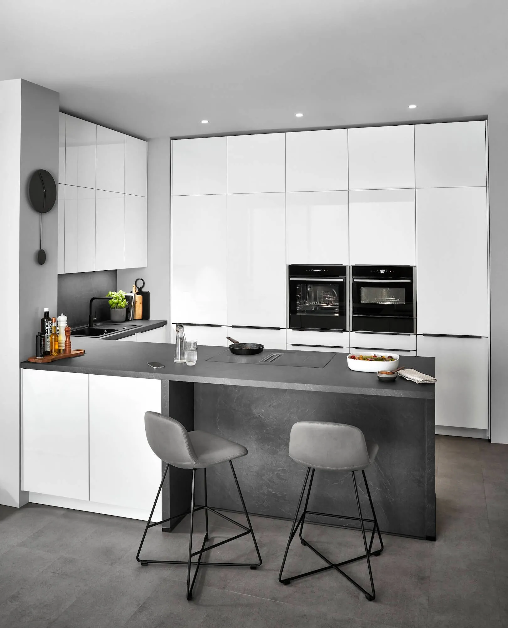 Cuisine optimisée blanche laquée avec îlot central noir, fours doubles et chaises hautes Cuisine optimisée blanche laquée avec îlot central noir, fours doubles et chaises hautes