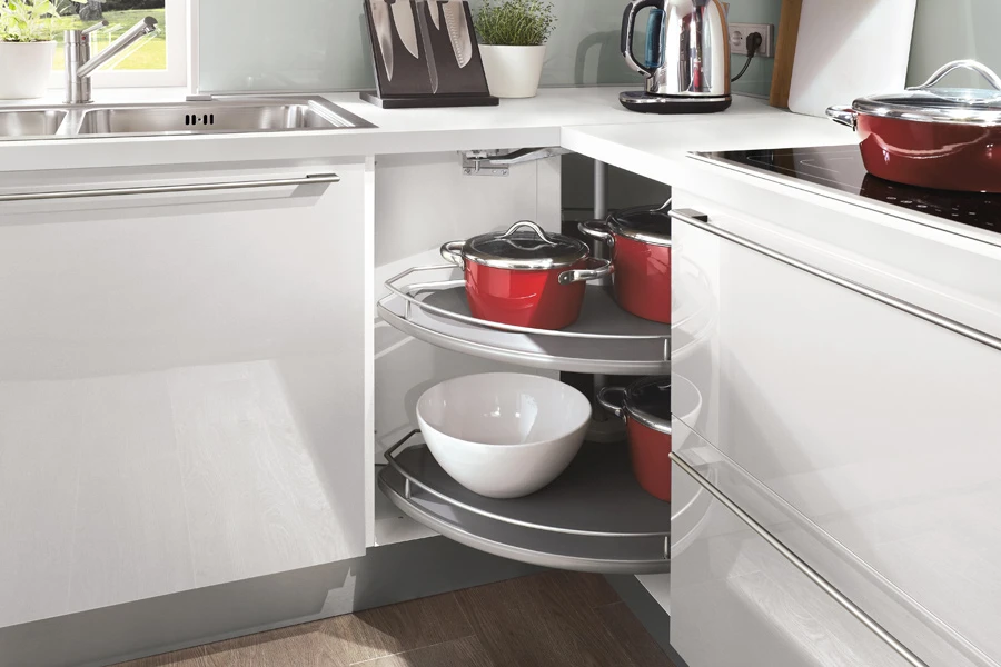 Meuble d'angle tourniquet blanc avec plateaux tournants et casseroles rouges rangées Meuble d'angle tourniquet blanc avec plateaux tournants et casseroles rouges rangées