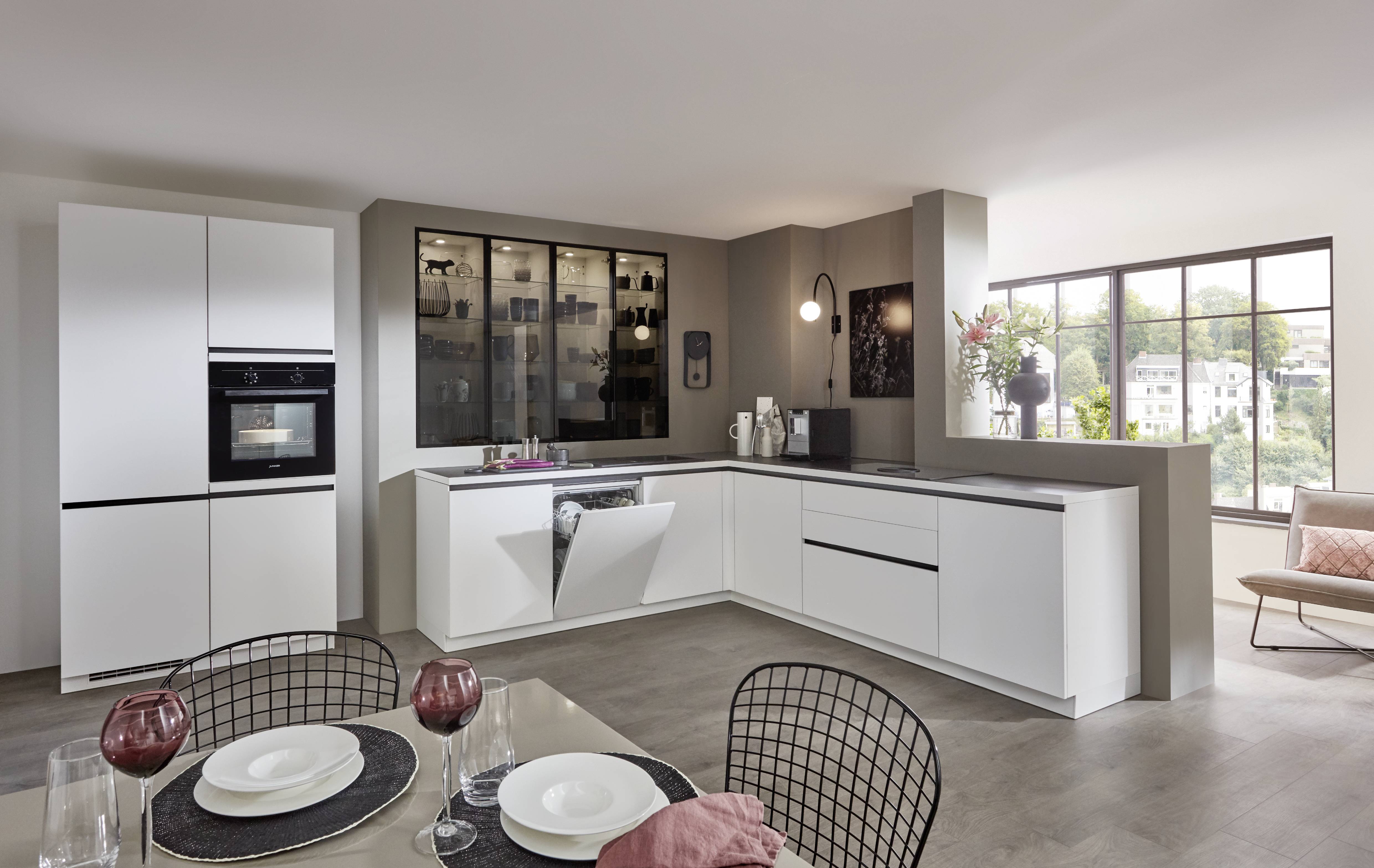 Cuisine en L sur mesure blanche avec plan de travail gris, électroménager intégré et nombreux rangements dans un espace ouvert. Cuisine en L sur mesure blanche avec plan de travail gris, électroménager intégré et nombreux rangements dans un espace ouvert.