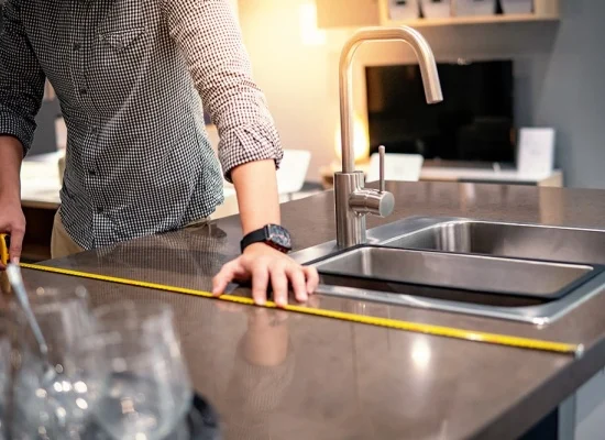 Technicien prenant les mesures d'un plan de travail pour une cuisine sur mesure Technicien prenant les mesures d'un plan de travail pour une cuisine sur mesure